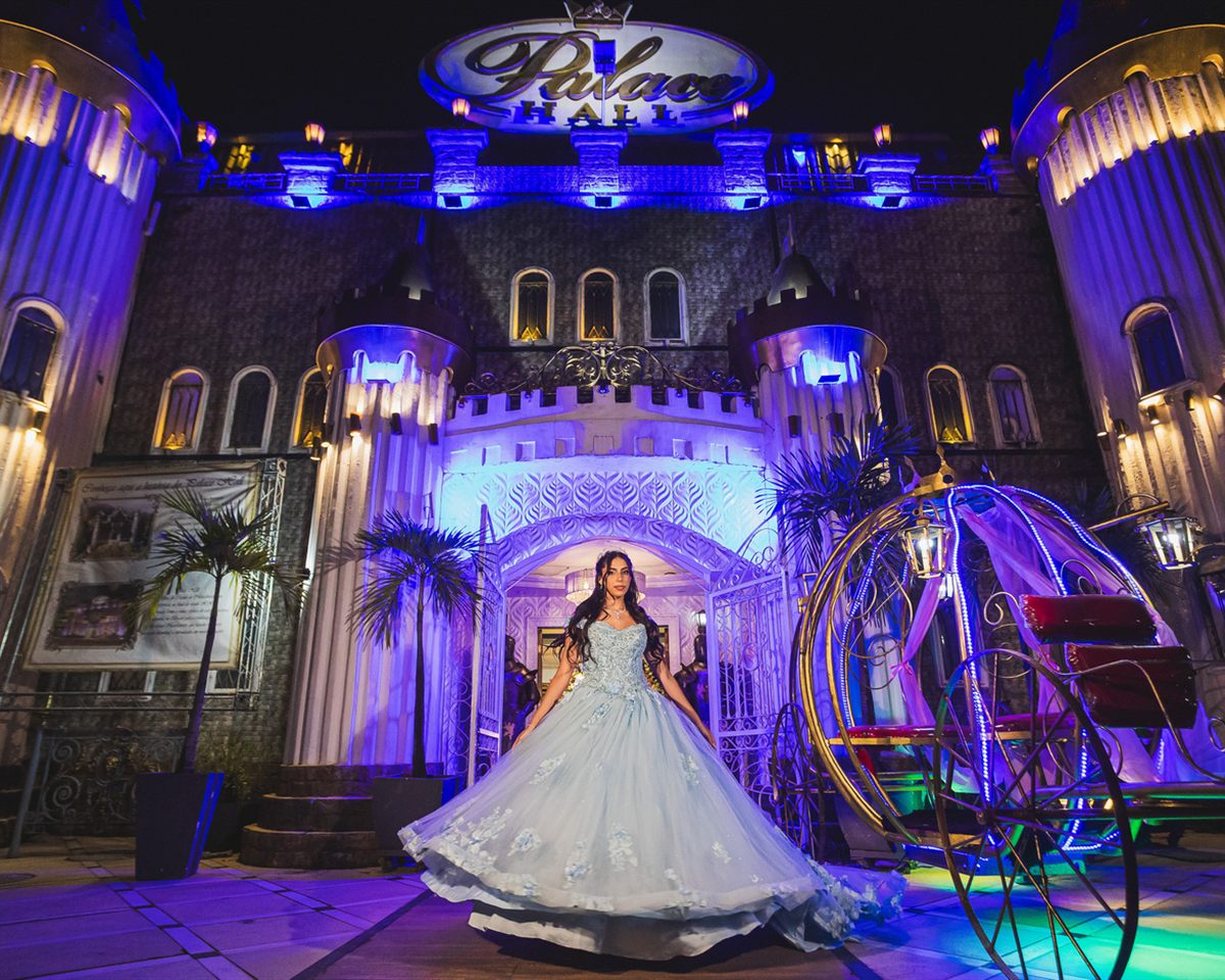 Debutante de vestido azul na frente do castelo do Palace Hall, com a carruagem de Cinderela