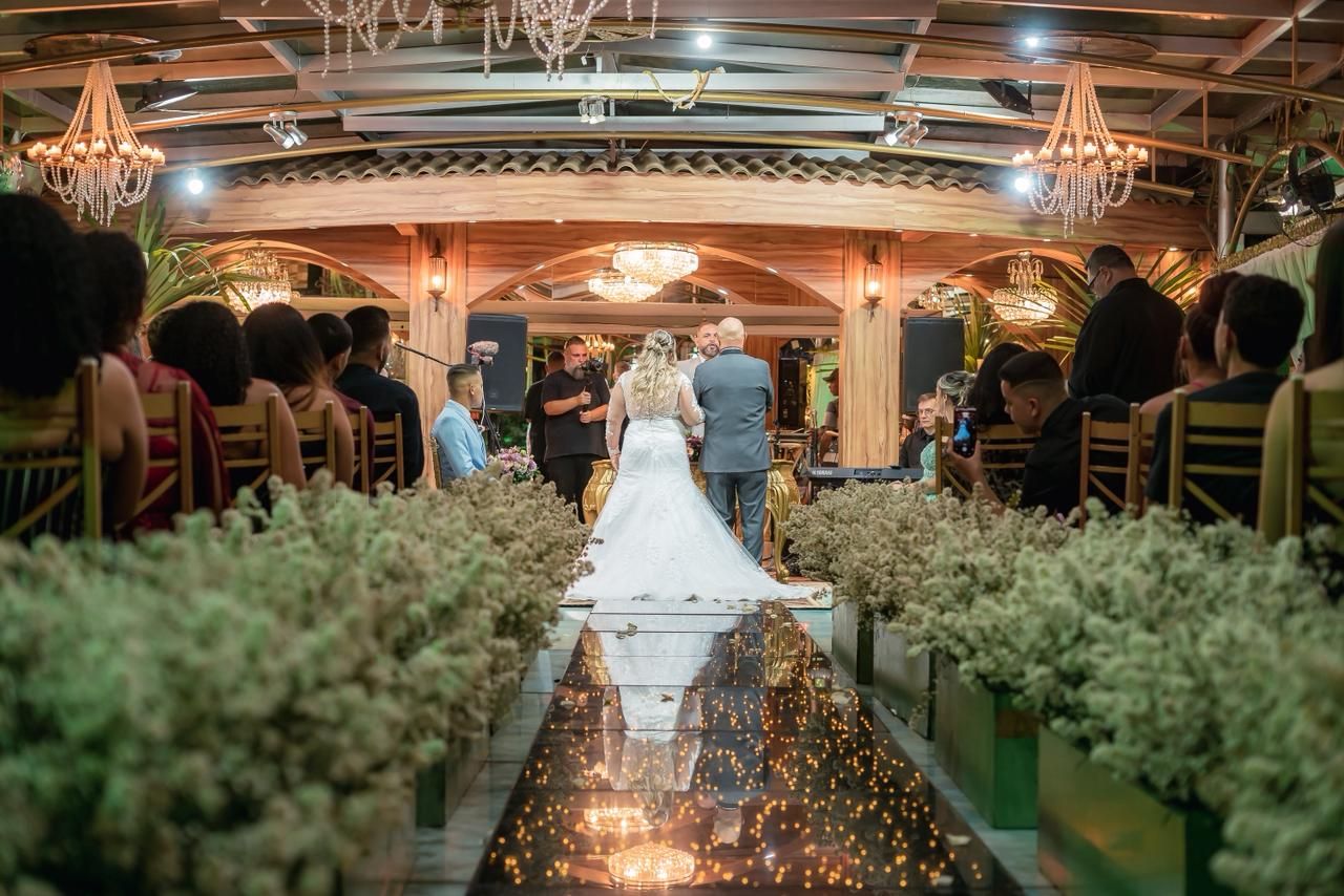 Noivos no altar, de costas, no corredor de flores da cerimônia
